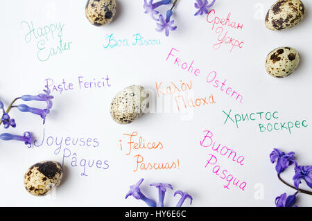 Happy Easter Hinweis in verschiedenen Sprachen und Wachtel-Eiern Stockfoto