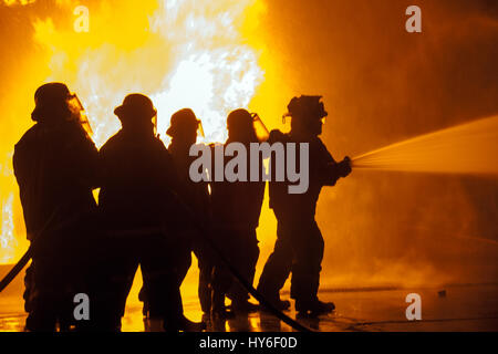 Gruppe der Feuerwehr Schlauch Besprühen mit Wasser während der Brandbekämpfung Übung zu kontrollieren Stockfoto