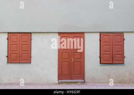 Fassade des alten Hauses mit hölzernen Tür und zwei geschlossene Fenster Stockfoto