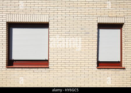 Windows mit geschlossenen Fensterläden auf einer weißen Hauswand Stockfoto