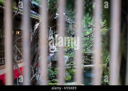 KYOTO, JAPAN - 10. Januar 2016: Japanische Mädchen in traditionellen Kimono in einem Zengarten in Kyoto sitzt. Kyoto ist das Kapital Stadt von Kyoto-Prefectur Stockfoto