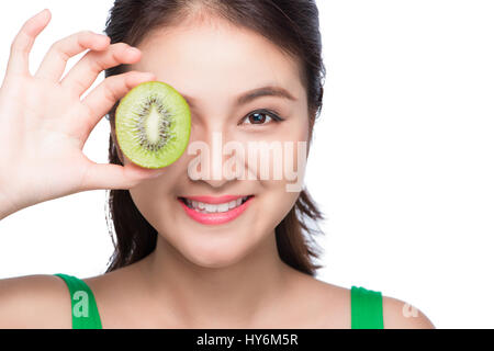 Tropische Früchte. Gesunde Ernährung. Charmante junge Asiatin halten frische saftige Kiwi und lächelt. Grünen Hintergrund. Stockfoto