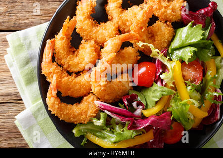 Gebratene Garnelen in Paniermehl und ein Salat aus frischem Gemüse Nahaufnahme auf einer Platte auf einem Tisch. horizontale Ansicht von oben Stockfoto