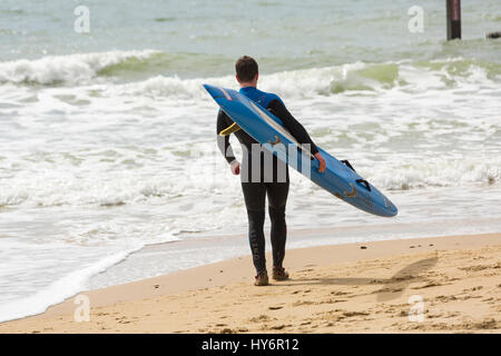 Bournemouth - Surfer mit Surfbrett ins Meer am Strand von Bournemouth im April Stockfoto