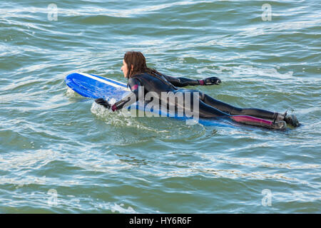 Bournemouth - Frau Surfer auf Surfbrett am Strand von Bournemouth liegt im April Stockfoto