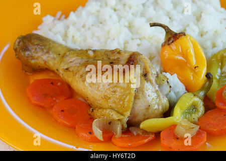 Gebratenes Huhn mit Reis, Karotten und Paprika auf orange Platte Stockfoto