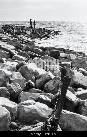 Schwarz-weiß Bild von zwei angler angeln von einem Felsvorsprung bei Kimmeridge Bay, Dorset, England, Großbritannien Stockfoto
