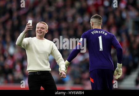Ein Stellplatz Eindringling versucht, ein Selbstporträt mit Southampton Torwart Fraser Forster während der Premier League match bei St Mary's, Southampton abzurufen. Stockfoto