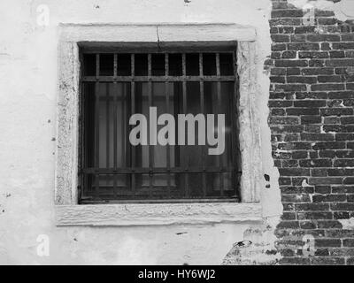 Alten vergitterten Fenster auf eine notleidende Mauer Stockfoto