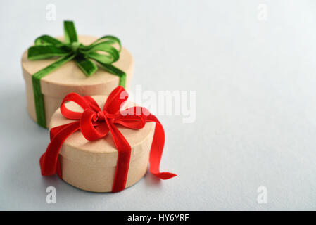 Runde Geschenkboxen mit roten und grünen Bändern auf blauem Hintergrund Stockfoto