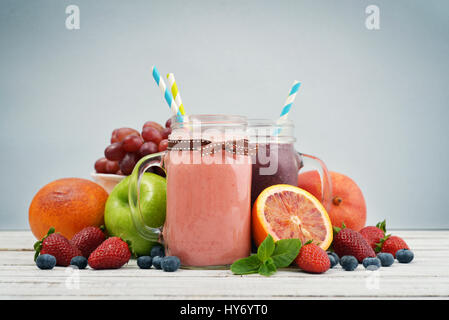 Glas mit Griff von Smoothies mit verschiedenen Beeren und Früchte auf blauem Hintergrund Stockfoto