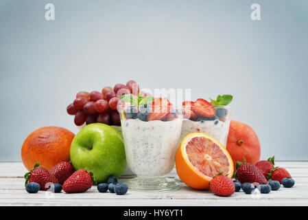 Pudding mit Chia-Samen, Joghurt und frisches Obst im Glas auf blauem Hintergrund Stockfoto