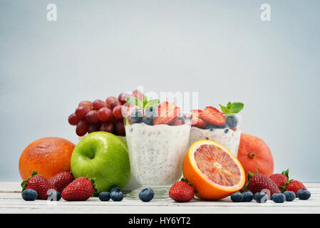 Pudding mit Chia-Samen, Joghurt und frisches Obst im Glas auf blauem Hintergrund Stockfoto