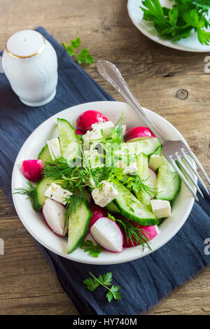 Frühling Gemüsesalat mit frischen Gurken, Radieschen, Feta-Käse, Kräuter, Gemüse, Sprossen in Schüssel auf hölzernen Hintergrund - gesunde Detox Bio-Ernährung vegan Stockfoto