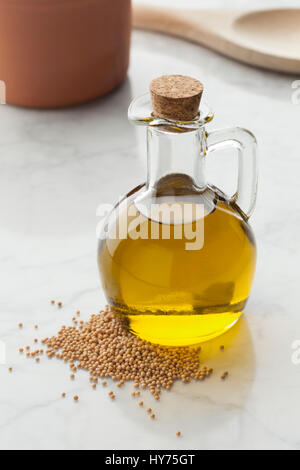 Glasflasche mit Senföl und ein Haufen von Samen Stockfoto