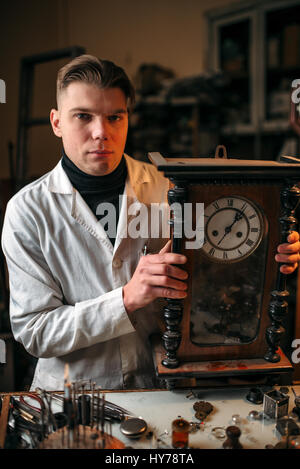 Uhrmacher stellt den Mechanismus der alte Wanduhr in der Werkstatt. Stockfoto