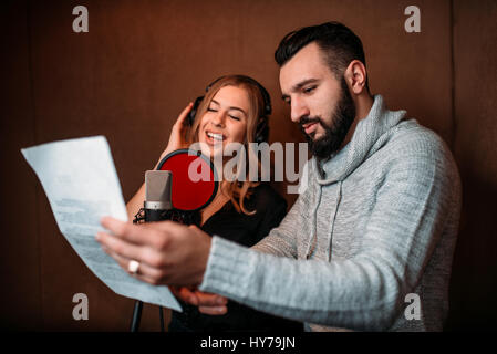 Musikproduzent zeigt Text Sängerin in Kopfhörer, Song-Rekord im Musikstudio. Sängerin Aufnahme audio-Track. Professionelle digitale sound Stockfoto