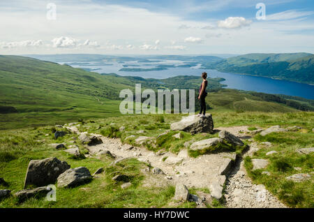 Weibliche Wanderer bewundern die Landschaft auf den Weg zum Gipfel des Ben Lomond an einem sonnigen Tag. Loch Lomond im Hintergrund. Schottland (UK). Stockfoto