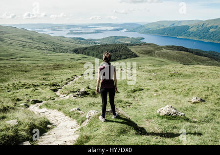 Weibliche Wanderer bewundern die Landschaft auf den Weg zum Gipfel des Ben Lomond an einem sonnigen Tag. Loch Lomond im Hintergrund. Schottland (UK). Stockfoto