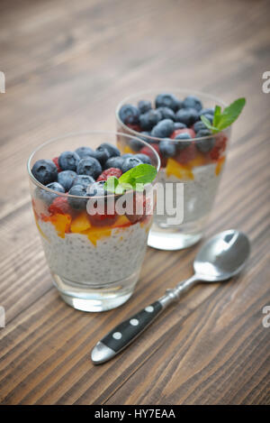 Pudding mit Chia-Samen, Joghurt und frische Beeren im Glas auf hölzernen Hintergrund Stockfoto