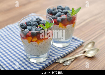 Pudding mit Chia-Samen, Joghurt und frische Beeren im Glas auf hölzernen Hintergrund Stockfoto