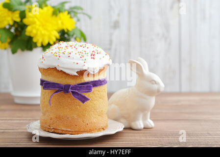 Osterkuchen auf Teller mit Kaninchen und Blumen auf hölzernen Hintergrund Stockfoto