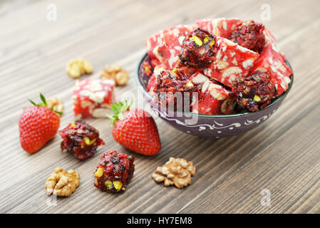 Turkish Delight mit Nüssen und Erdbeere in Keramikschale auf hölzernen Hintergrund Stockfoto