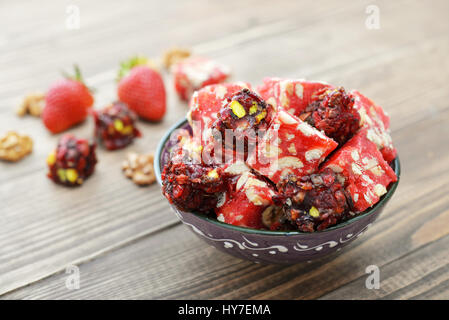 Turkish Delight mit Nüssen und Erdbeere in Keramikschale auf hölzernen Hintergrund Stockfoto