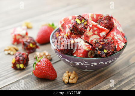 Turkish Delight mit Nüssen und Erdbeere in Keramikschale auf hölzernen Hintergrund Stockfoto