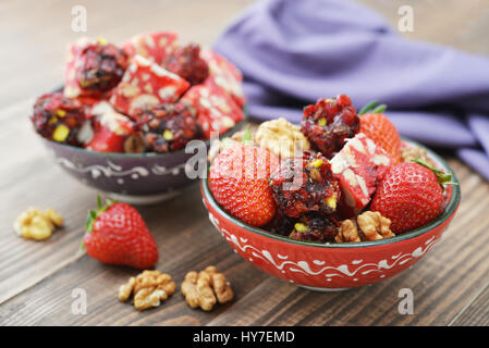 Turkish Delight mit Nüssen und Erdbeere in Keramikschale auf hölzernen Hintergrund Stockfoto