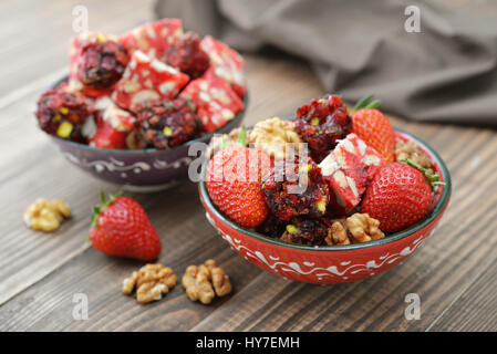 Turkish Delight mit Nüssen und Erdbeere in Keramikschale auf hölzernen Hintergrund Stockfoto