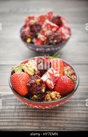 Turkish Delight mit Nüssen und Erdbeere in Keramikschale auf hölzernen Hintergrund Stockfoto