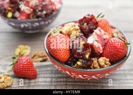 Turkish Delight mit Nüssen und Erdbeere in Keramikschale auf hölzernen Hintergrund Stockfoto