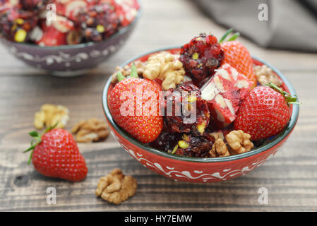 Turkish Delight mit Nüssen und Erdbeere in Keramikschale auf hölzernen Hintergrund Stockfoto