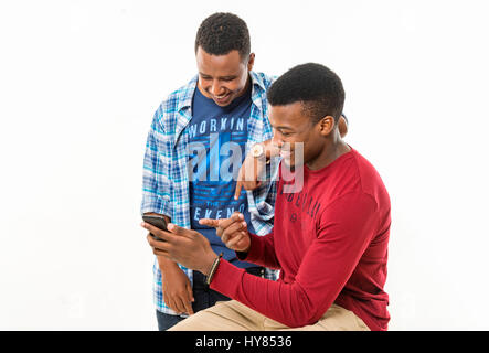 Afrikanische männliche Freunde schauen sich gemeinsam ein mobiles Gerät an. Stockfoto