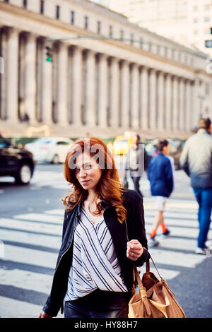 Junge Frauen, die zu Fuß entlang einer New Yorker Straße mit Blick auf die Kamera an einem sonnigen Tag Stockfoto