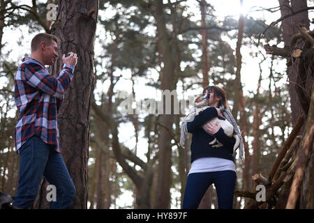 Ein Mann nimmt ein Foto von seiner Gefährtin und ihr Hund, wie sie in den Wald gehen Stockfoto