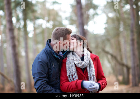 Ein junges Paar küssen sich bei einem Spaziergang im Wald Stockfoto