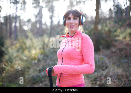 Eine junge Frau mit Kopfhörern während des Trainings im Wald Stockfoto