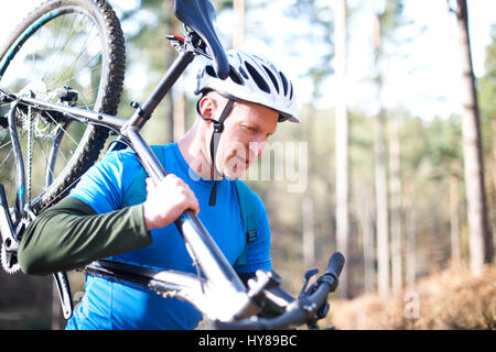 Ein Mann trägt seinem Mountainbike im Wald Stockfoto