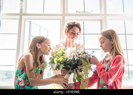 Eine Braut mit ihrem Zwilling Brautjungfern hält einen Blumenstrauß vor ihrer Hochzeit Stockfoto