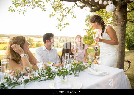 Eine Braut und Bräutigam sitzen am Tisch mit ihren Freunden bei einem externen Hochzeit Stockfoto