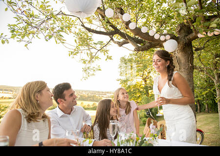 Eine Braut und Bräutigam sitzen am Tisch mit ihren Freunden bei einem externen Hochzeit Stockfoto