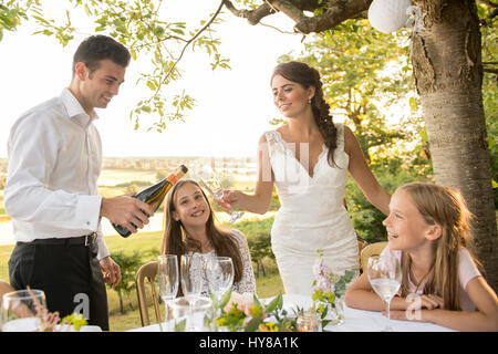 Eine Braut und Bräutigam sitzen am Tisch mit ihren Freunden bei einem externen Hochzeit Stockfoto