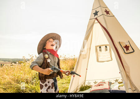 Ein kleiner Junge spielt Cowboys und Indianer draußen in der Sonne Stockfoto