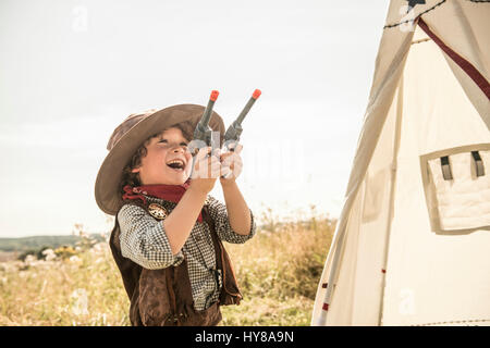 Ein kleiner Junge spielt Cowboys und Indianer draußen in der Sonne Stockfoto