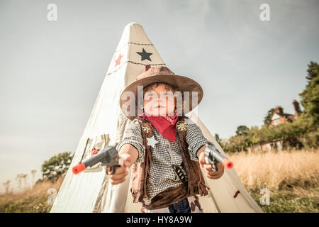 Ein kleiner Junge spielt Cowboys und Indianer draußen in der Sonne Stockfoto