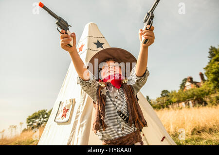 Ein kleiner Junge spielt Cowboys und Indianer draußen in der Sonne Stockfoto