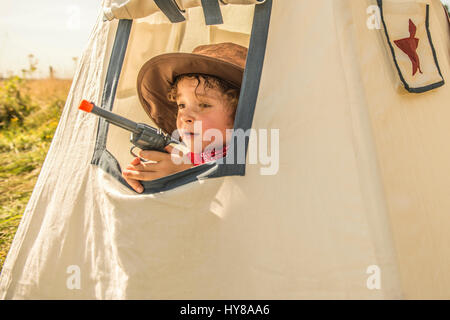 Ein kleiner Junge spielt Cowboys und Indianer draußen in der Sonne Stockfoto