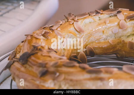 Frisch gebackene leckere Windbeutel mit Schokolade und gerösteten Mandeln Flocken auf einem Teller abkühlen bedeckt. Beliebtes Französisches Dessert. Stockfoto